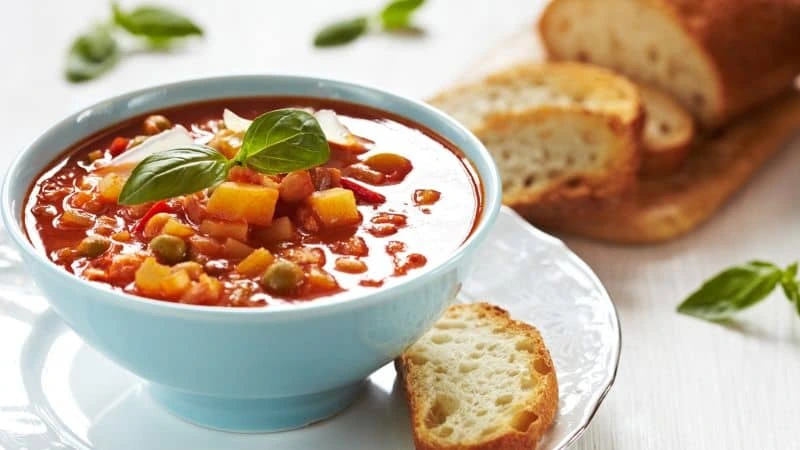 Sopa cremosa de feijão servida em tigela branca, acompanhada de torradas